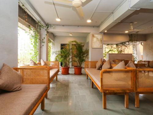 a restaurant with benches and tables and potted plants at Hotel Tattva Suites in Pune