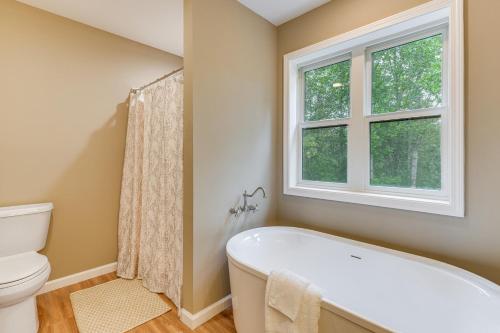 La salle de bains est pourvue d'une baignoire blanche et d'une fenêtre. dans l'établissement Long-Range Views Blue Ridge Mtn Cabin with 3 Decks, à Bakersville