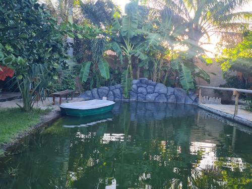 a small boat in a pond in a yard at Chalés Refúgio Fortim in Fortim