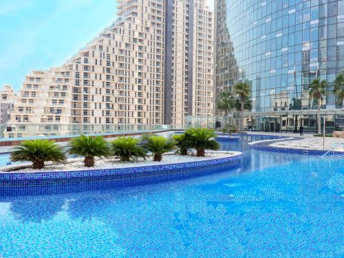 a large swimming pool in a city with tall buildings at Pearl Club Al Reem Island 2 Bedrooms With Pool , Gym and Tennis Court in Abu Dhabi