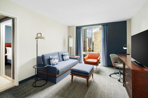 a hotel room with a blue couch and a desk at Courtyard New York Manhattan/Upper East Side in New York