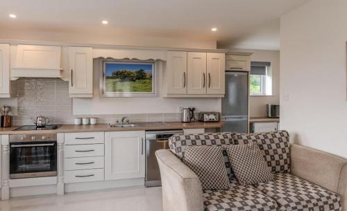 a kitchen with white cabinets and a couch at Inis Beag - Your Gweedore Getaway in Gweedore