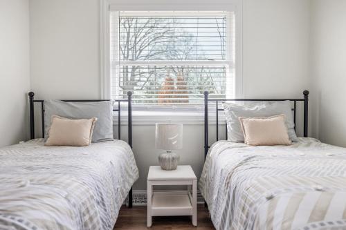 two beds in a white room with a window at Rocky Gap Getaway in Benton Harbor
