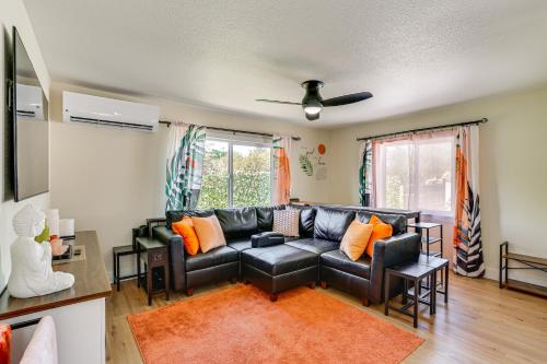 a living room with a black leather couch and orange pillows at Walkable and Bright Bungalow in Dtwn Redding! in Redding