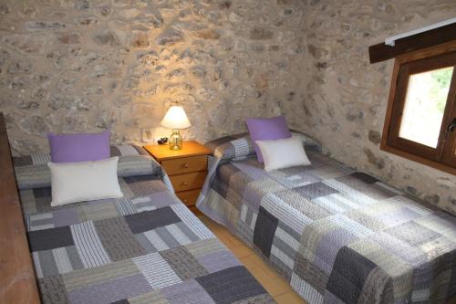 two twin beds in a room with stone walls at Mas De Rogelio in Beceite