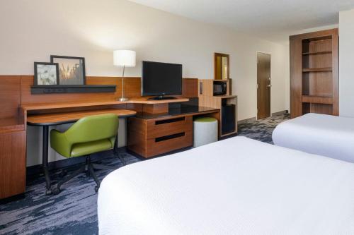 a hotel room with a desk with a computer and a bed at Fairfield Inn & Suites by Marriott Wentzville in Wentzville