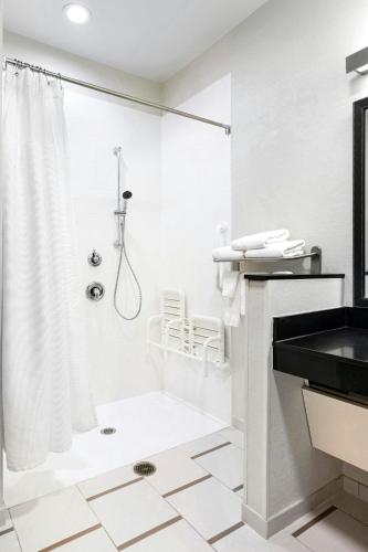 a white bathroom with a shower and a sink at Fairfield Inn & Suites by Marriott Wentzville in Wentzville