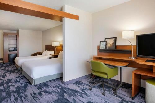 a hotel room with a desk and a bed and a computer at Fairfield Inn & Suites by Marriott Wentzville in Wentzville