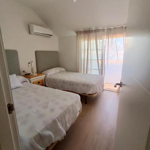 a hotel room with two beds and a window at Dúplex Frente al Mar - Salobreña in Salobreña