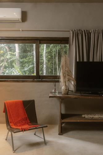 a living room with a table and a chair and a television at CASA SUKHA Hotel in Trancoso