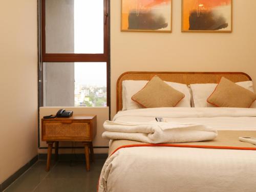 a room with two beds and a table with a window at Hotel Tattva Suites in Pune