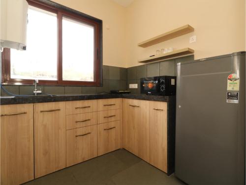 a kitchen with a stainless steel refrigerator and wooden cabinets at Hotel Tattva Suites in Pune