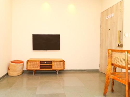 a living room with a tv on a white wall at Hotel Tattva Suites in Pune