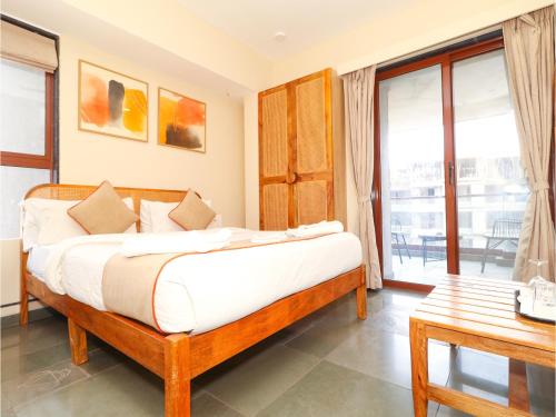 a bedroom with a bed and a table and a window at Hotel Tattva Suites in Pune