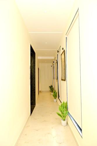 a corridor with white walls and a hallway with potted plants at JMD Royal Residency I Luxury 3-Star Hotel in Varanasi