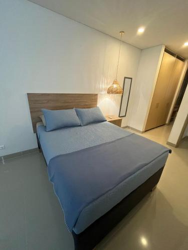 a bedroom with a large bed with blue sheets at Reserva Del Mar Apartamentos in Gaira