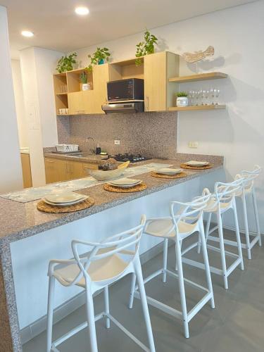 a kitchen with a counter with four stools at Reserva Del Mar Apartamentos in Gaira