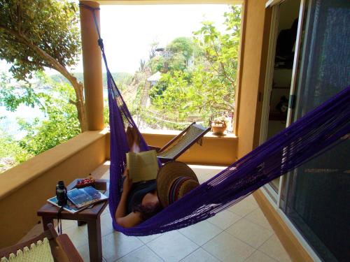 a woman laying in a hammock with a laptop at Hotel Casa Pan de Miel (Only Adults) in Mazunte