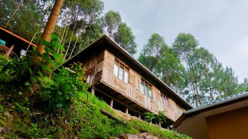 a wooden house on a hill with trees in the background at Rushaga Gorilla Lodge in Bugambira