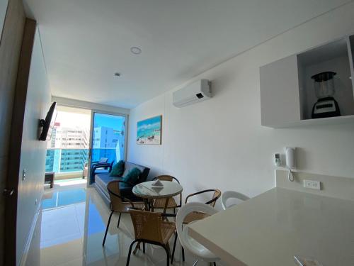 a kitchen and a living room with a table and chairs at Reserva Del Mar Apartamentos in Gaira