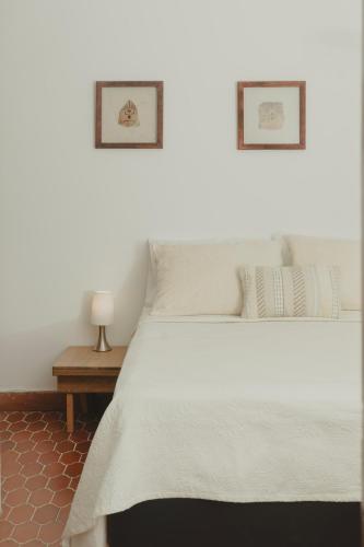 a bedroom with a white bed with two pictures on the wall at Cabecera House in Bucaramanga