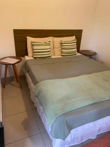 a bedroom with a bed with two pillows and a table at Vale do Pontal Angra Suites in Angra dos Reis