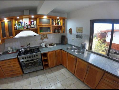 una cucina con mobili in legno e un forno a piano cottura di Carlos Paz Hostel Lodge a Villa Carlos Paz