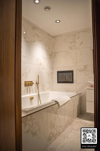 a bathroom with a tub and marble walls at SAINT PAUL - Unrivalled 3BR Penthouse Apartment with Hot Tub Leeds in Leeds