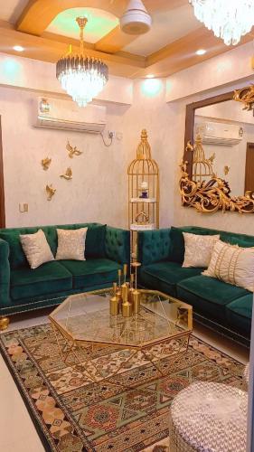a living room with green couches and a mirror at SeaView 2BR with parking, Walk to Dolmen Mall & Park in Karachi