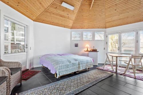 a bedroom with a bed and a table and windows at 1060-Thisted-Rodals-Bakke-21 in Torsted