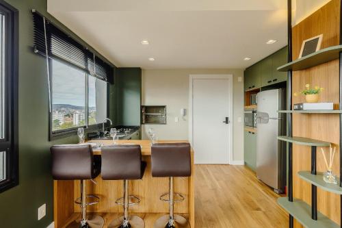 a kitchen with green walls and a counter with bar stools at Novíssimo: Go Carlos Gomes - Infra estrutura e Vista Espetacular! in Porto Alegre
