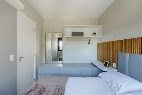 a bedroom with a bed and a sink and a mirror at Novíssimo: Go Carlos Gomes - Infra estrutura e Vista Espetacular! in Porto Alegre