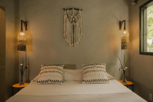 a bedroom with a large white bed with two pillows at CASA SUKHA Hotel in Trancoso