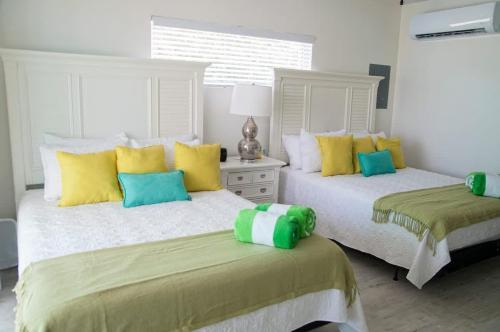 two beds with yellow and blue pillows in a bedroom at The Banana Bird at Cottages in Sand Bluff