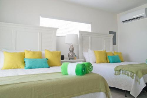 two beds with colorful pillows on them in a bedroom at The Banana Bird at Cottages in Sand Bluff