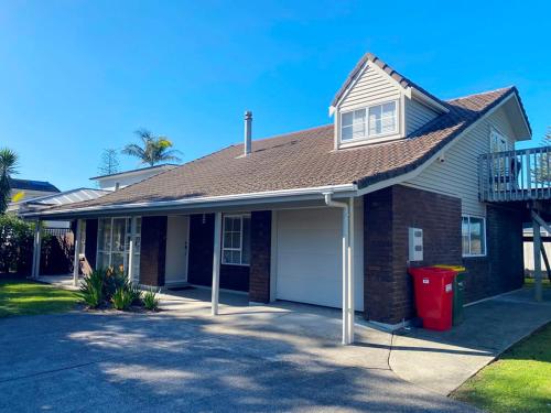 a house with a red trash can in front of it at Orewa Beach House in Orewa