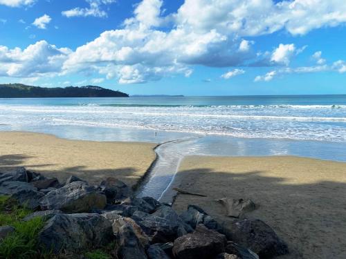 a beach with rocks on the sand and the ocean at Orewa Beach House in Orewa