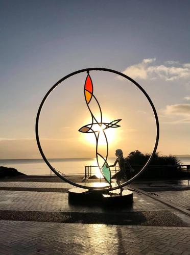a person standing in front of a large metal sculpture at Orewa Beach House in Orewa