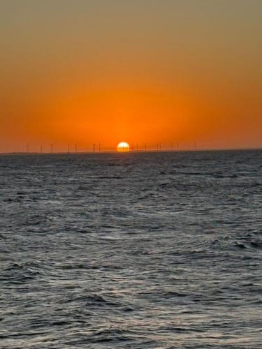 an orange sunset over the ocean with wind turbines at Chalés Refúgio Fortim in Fortim
