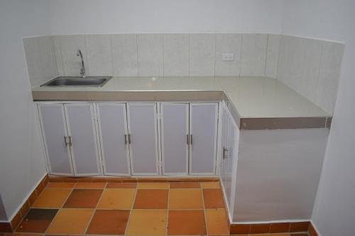 an empty kitchen with white cabinets and a sink at Finca La Fortaleza in Tuluá