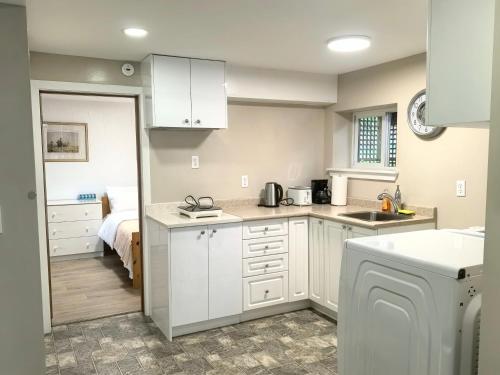 a kitchen with white cabinets and a bed in a room at Private Cozy 2bdrm Sleep5pp Metrotown! Free Parking! Self Check-in! in Burnaby