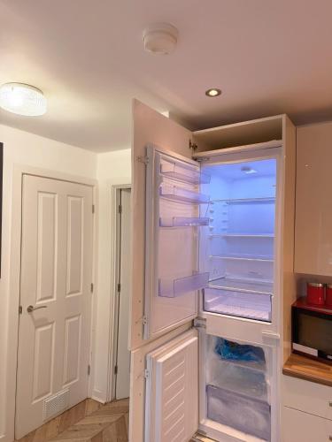 an empty refrigerator with its door open in a kitchen at Modern Home with Private Garden and Car Park in Manchester in Little Hulton