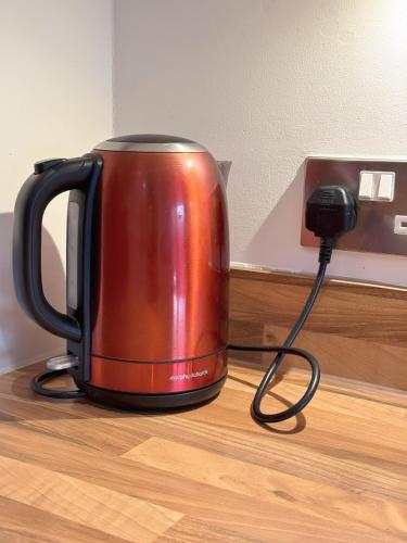 a red tea kettle sitting on top of a table at Modern Home with Private Garden and Car Park in Manchester in Little Hulton