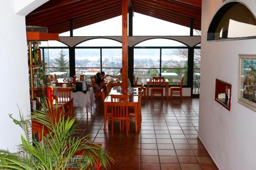 un restaurante con mesas, sillas y ventanas en Portal de la Montaña en Villa Carlos Paz