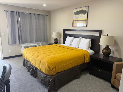 a bedroom with a large bed with a yellow blanket at American Inn & Suites LAX in Inglewood