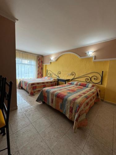 a hotel room with two beds and a window at Hotel Mezvall in Morelia