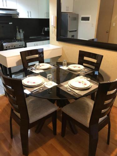 a black dining room table with chairs and plates on it at Departamento Condominio Club Carabayllo in Carabayllo