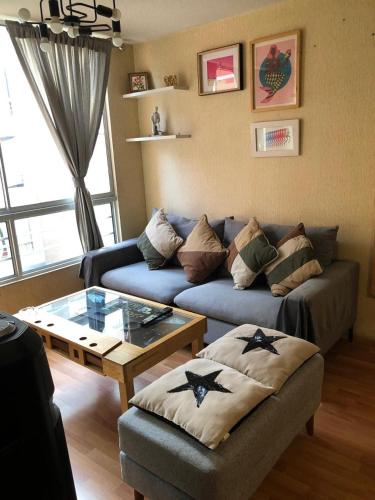 a living room with a blue couch and a glass table at Departamento Condominio Club Carabayllo in Carabayllo