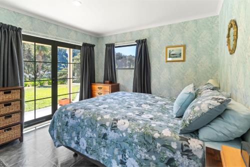 a bedroom with a bed with a blue comforter at Hill Cottage - Featherston Holiday Home in Featherston