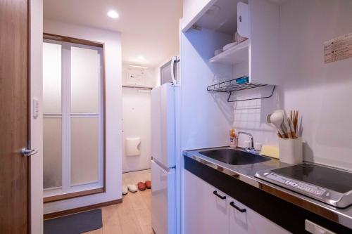 a small kitchen with a sink and a refrigerator at Sand Beige 7mins yokosukachuo station 2-4pax in Yokosuka